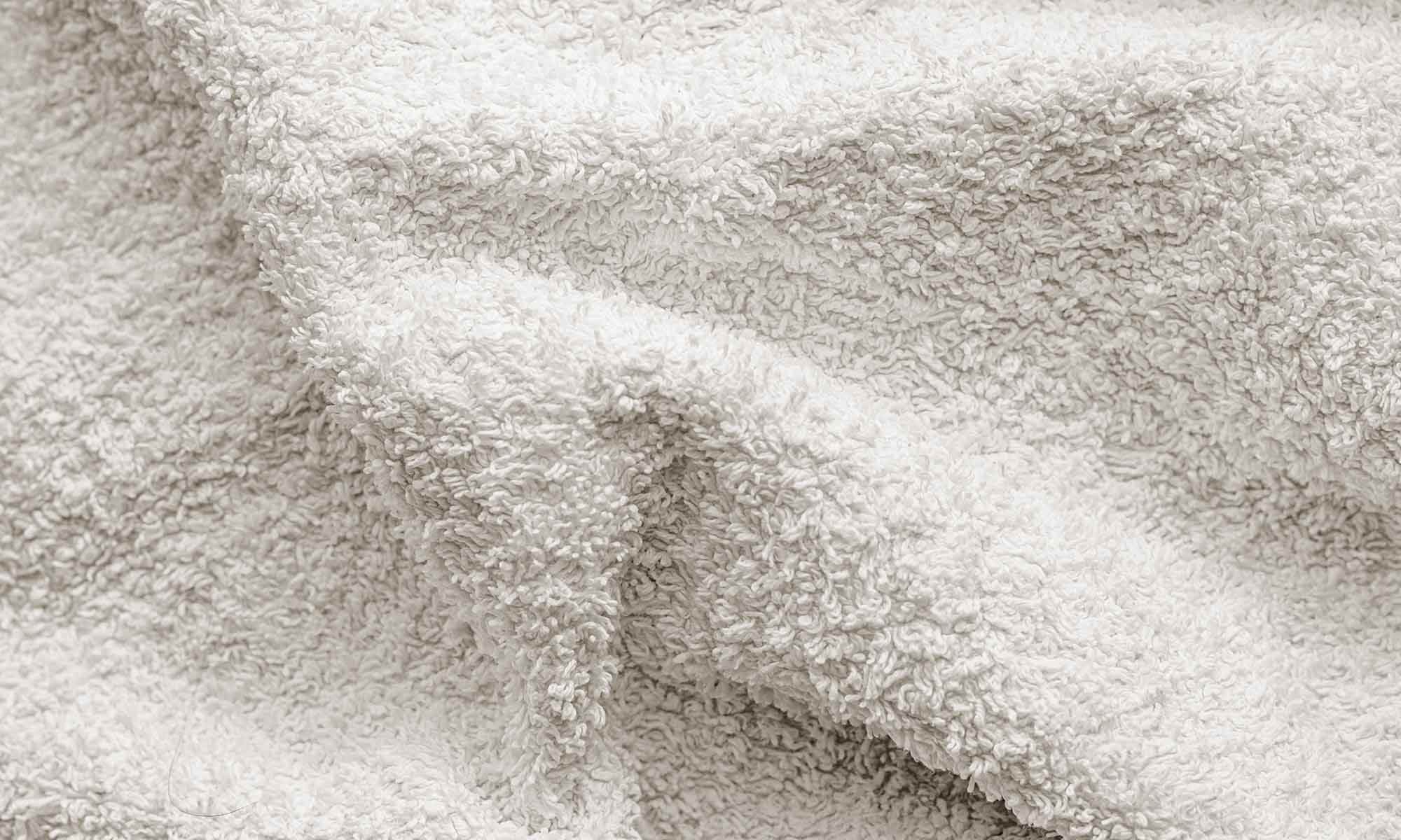 Nahaufnahme eines weißen, weichen Handtuchs mit sichtbaren Schlaufen und Falten.