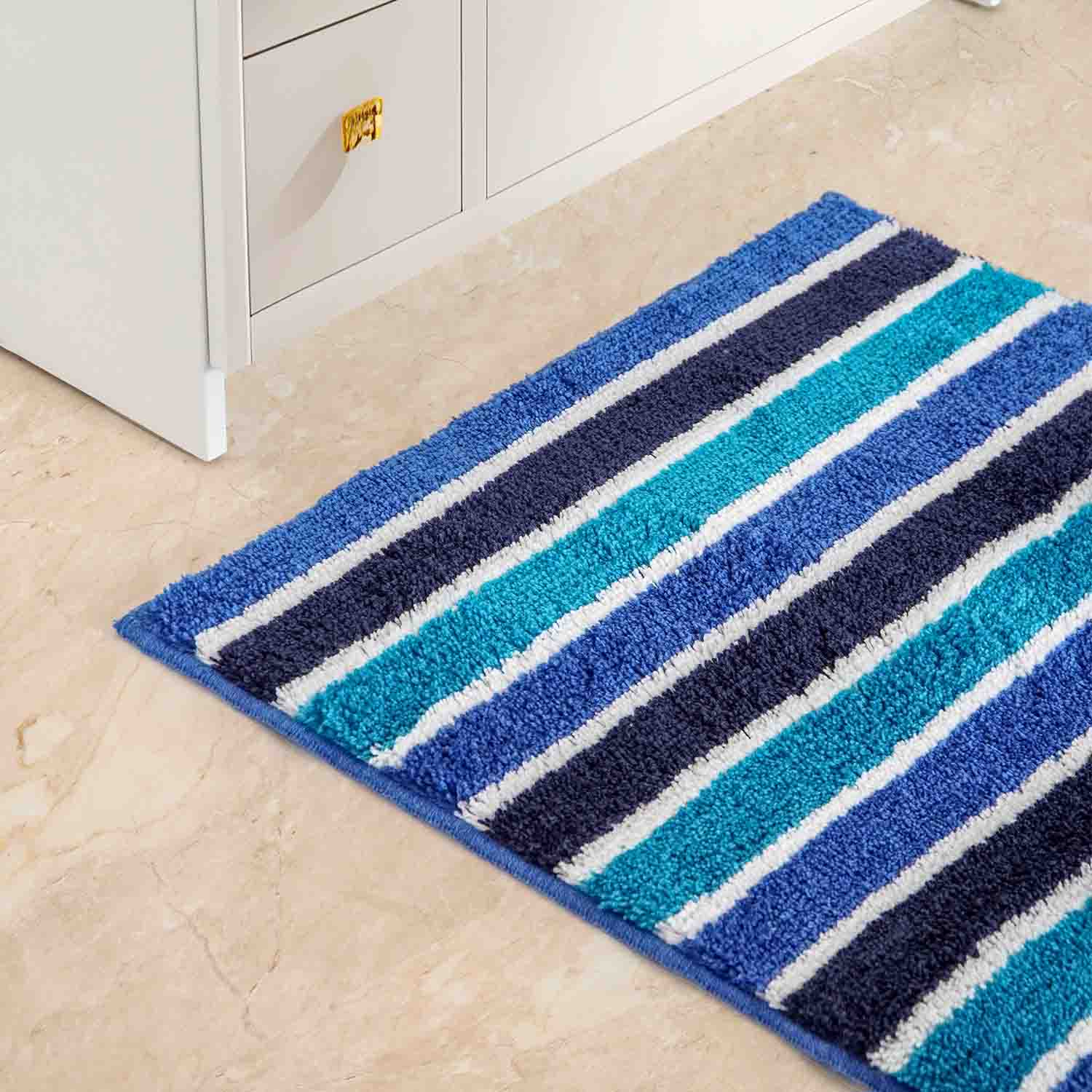 Ausschnitt eines blau gestreiften Badeteppichs liegend auf einem hellen Fußboden.