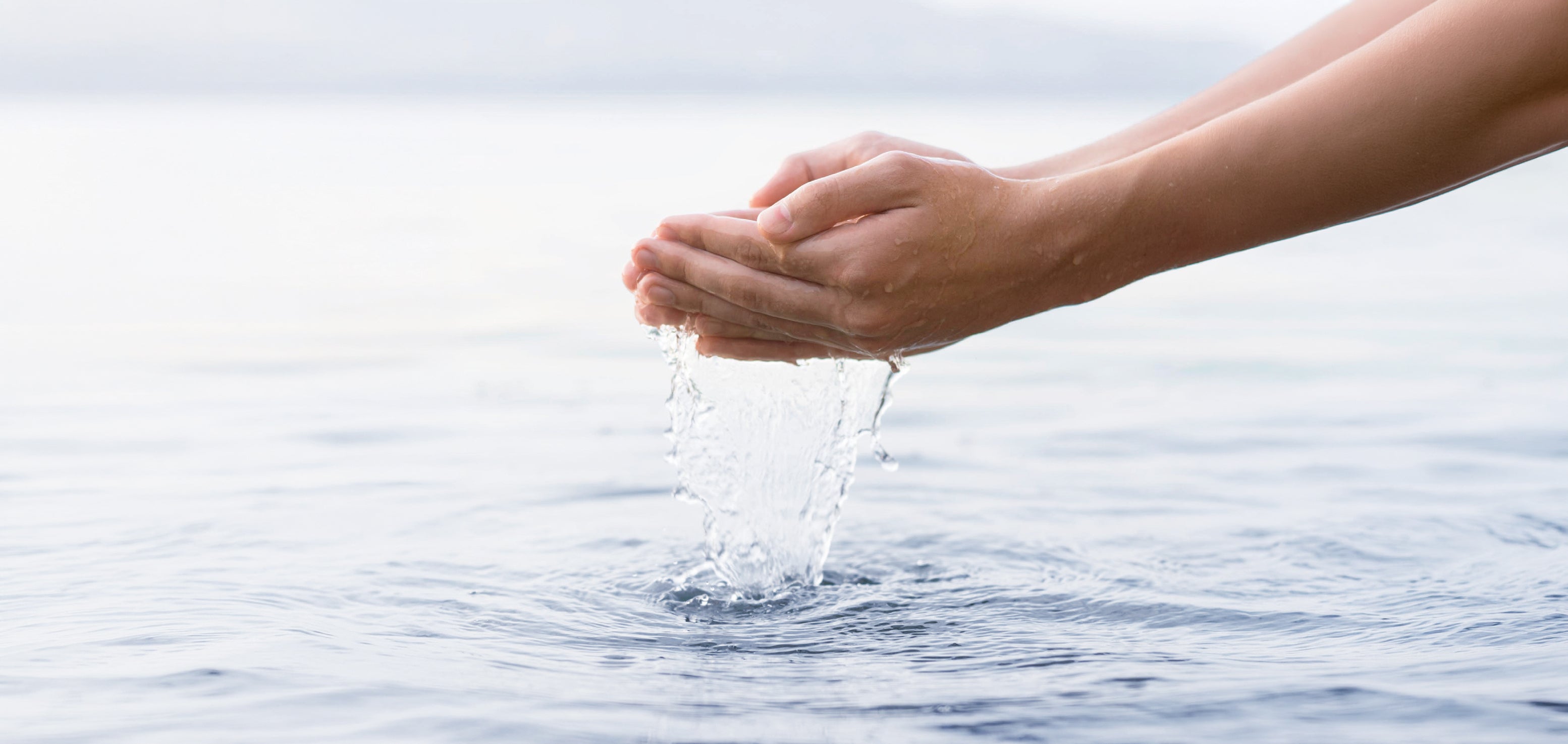 Hände schöpfen Wasser aus ruhiger Wasseroberfläche