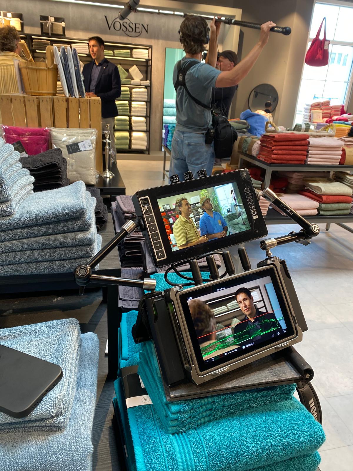 Filmaufnahmen in einem VOSSEN Store mit professionellem Produktionsteam, Kamera-Monitoren und Präsentation verschiedener Handtücher.