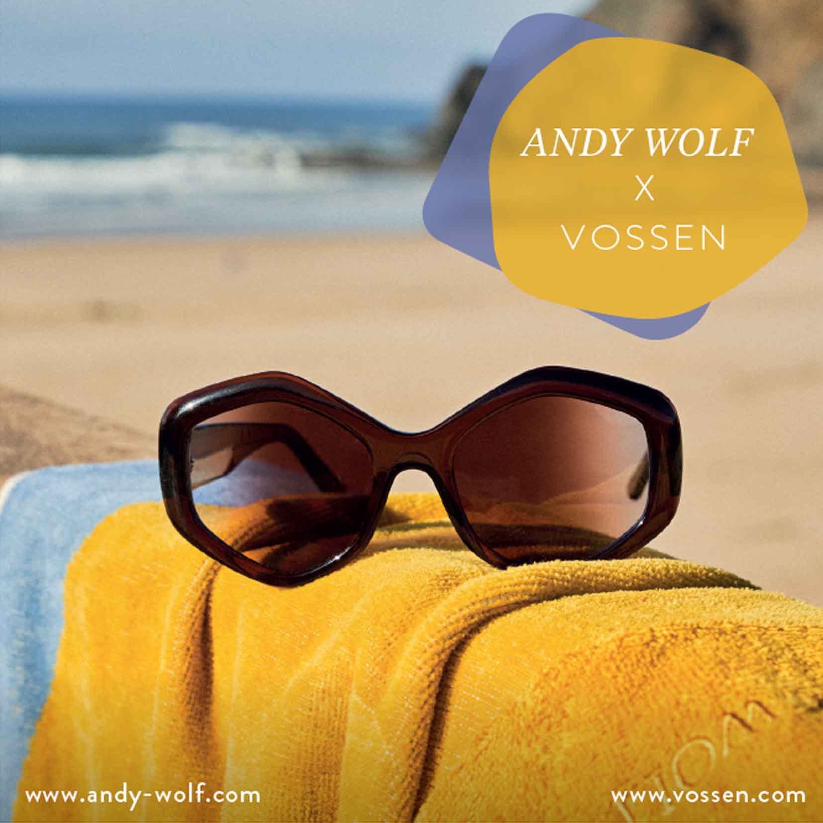 Große dunkle Sonnenbrille liegt auf einem gelben Handtuch am Strand. Im Hintergrund unscharf Meer und Felsen. Text: ‚ANDY WOLF X VOSSEN‘ sowie die Webseiten ‚www.andy-wolf.com‘ und ‚www.vossen.com‘.