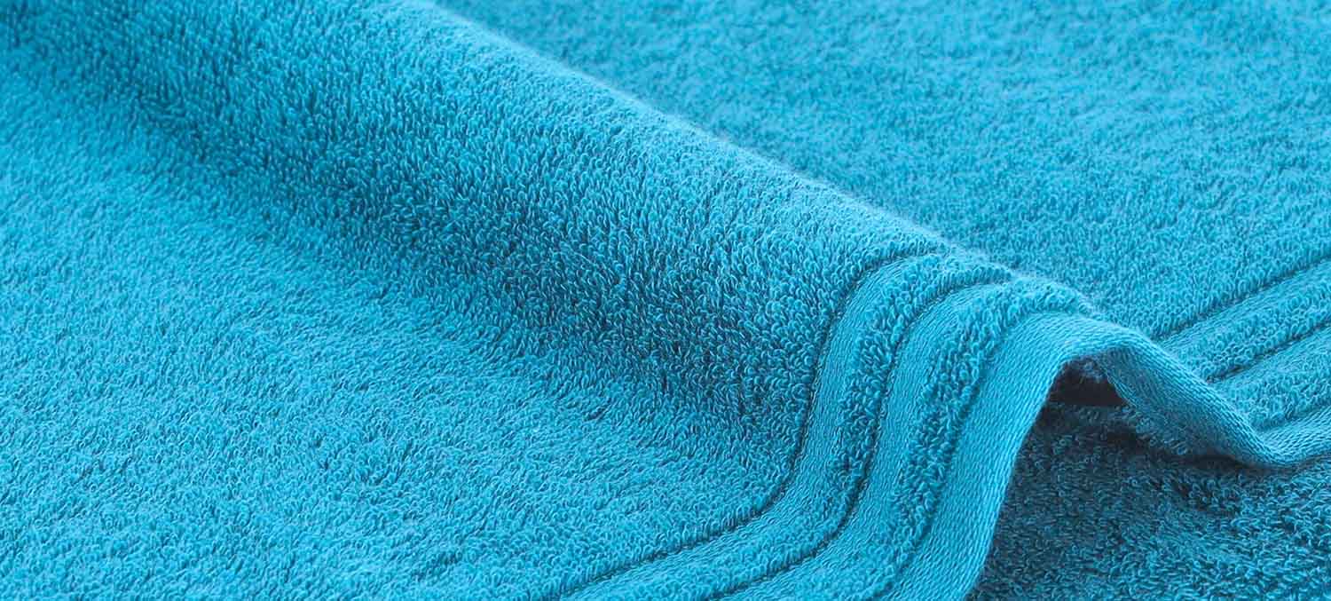 Nahaufnahme eines hellblauen Handtuchs mit strukturierter Oberfläche und gefalteten Kanten.