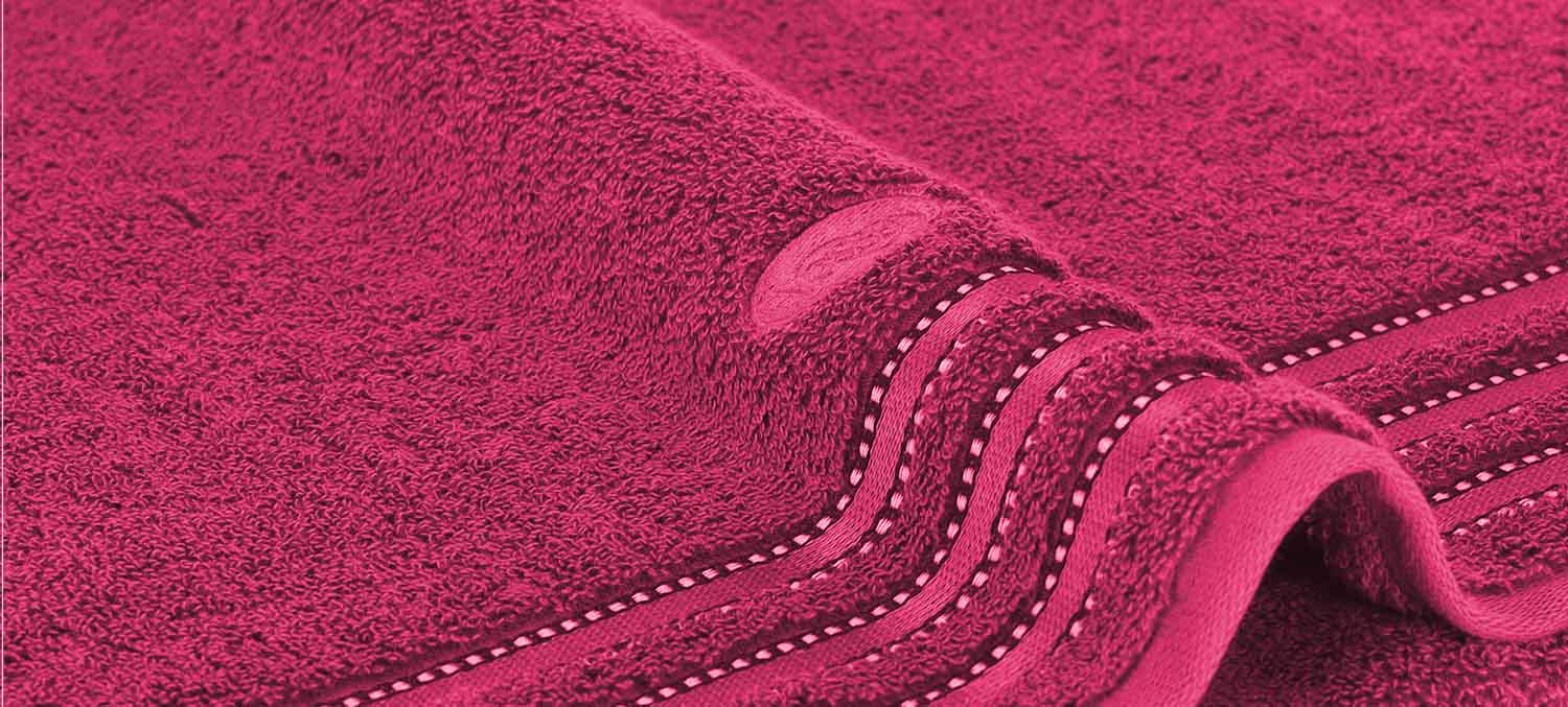 Nahaufnahme eines pinken Handtuchs mit strukturierter Oberfläche und gefalteten Kanten.