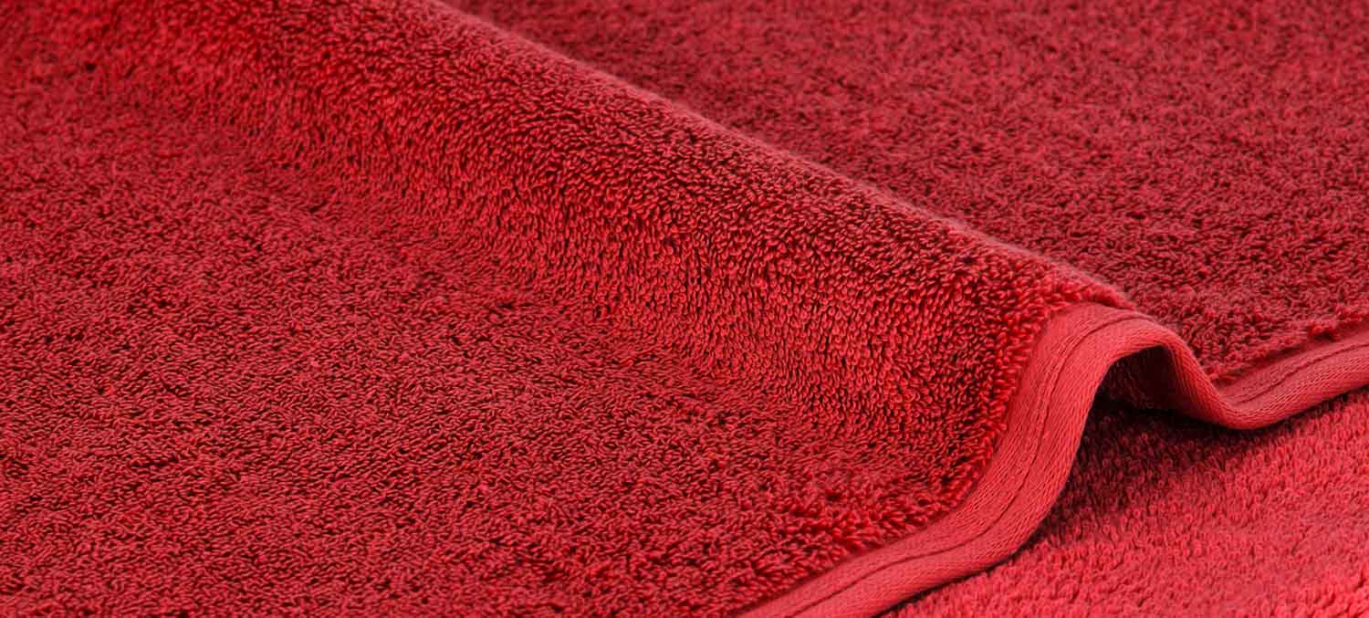 Nahaufnahme eines roten Handtuchs mit strukturierter Oberfläche und gefalteten Kanten.