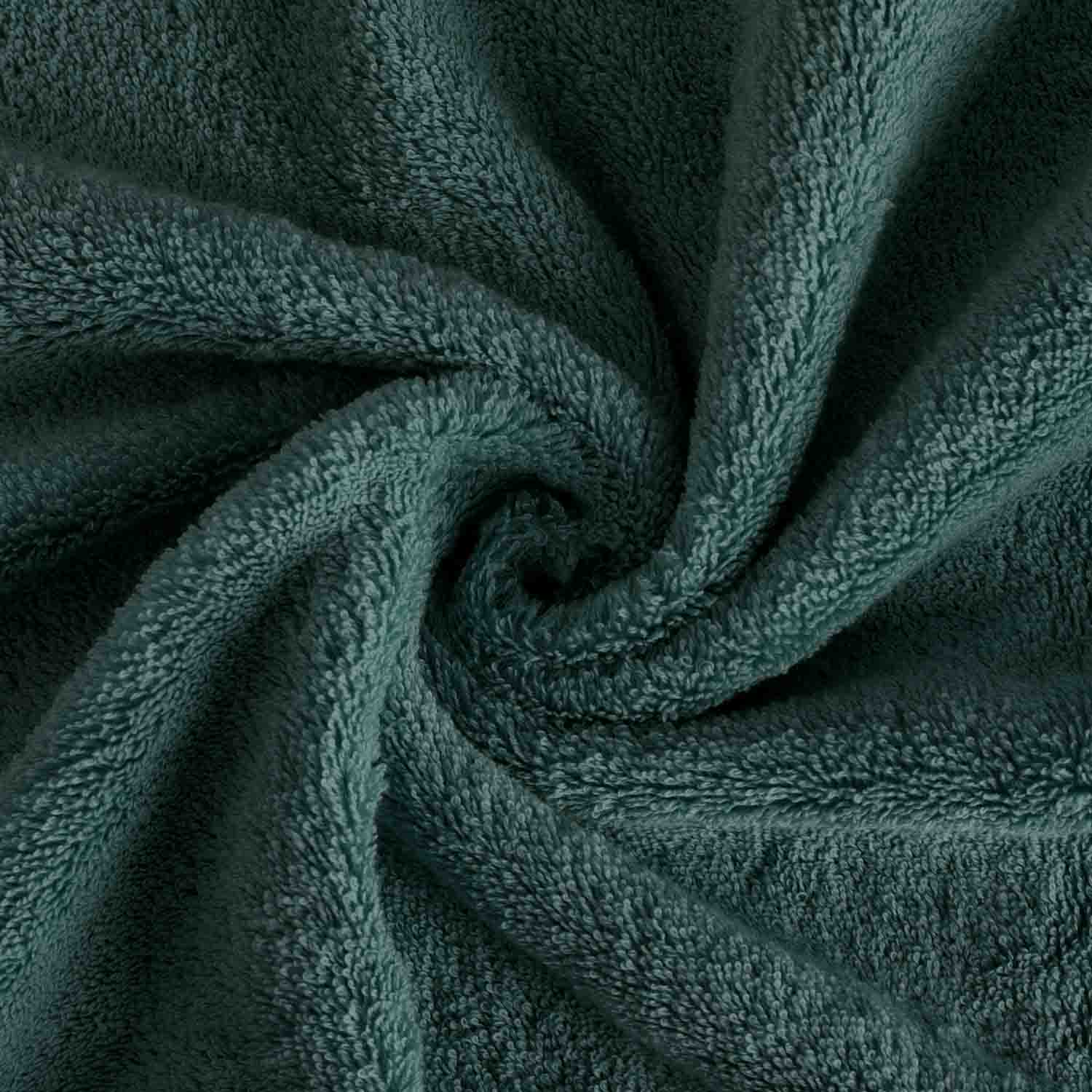 Dunkelgrünes Frottierhandtuch in Vogelperspektive eingedreht in einen Wirbel.