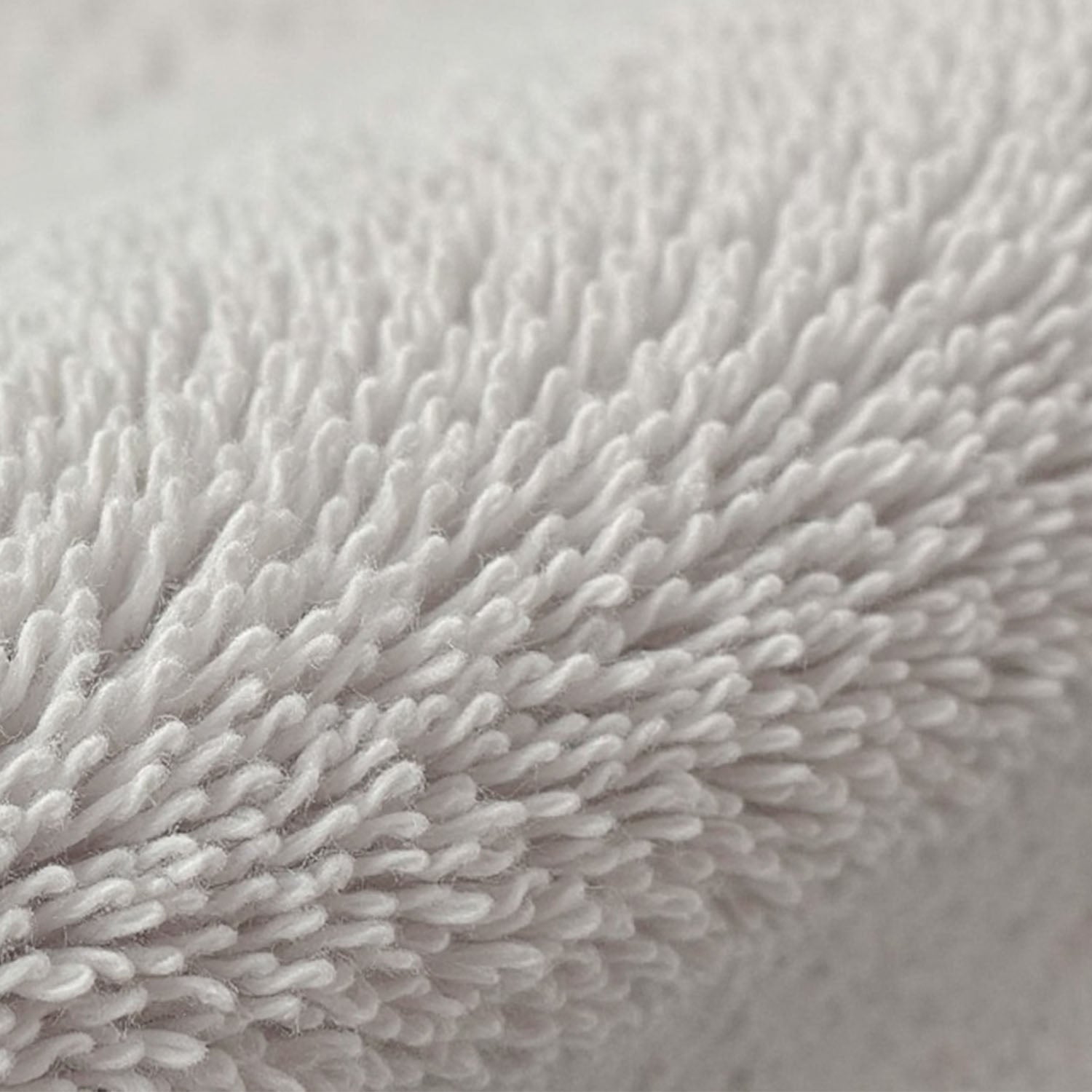 Detailreiche Ansicht der weichen, hochflorigen Schlingenstruktur eines weißen Handtuchs, die die flauschige Textur betont.
