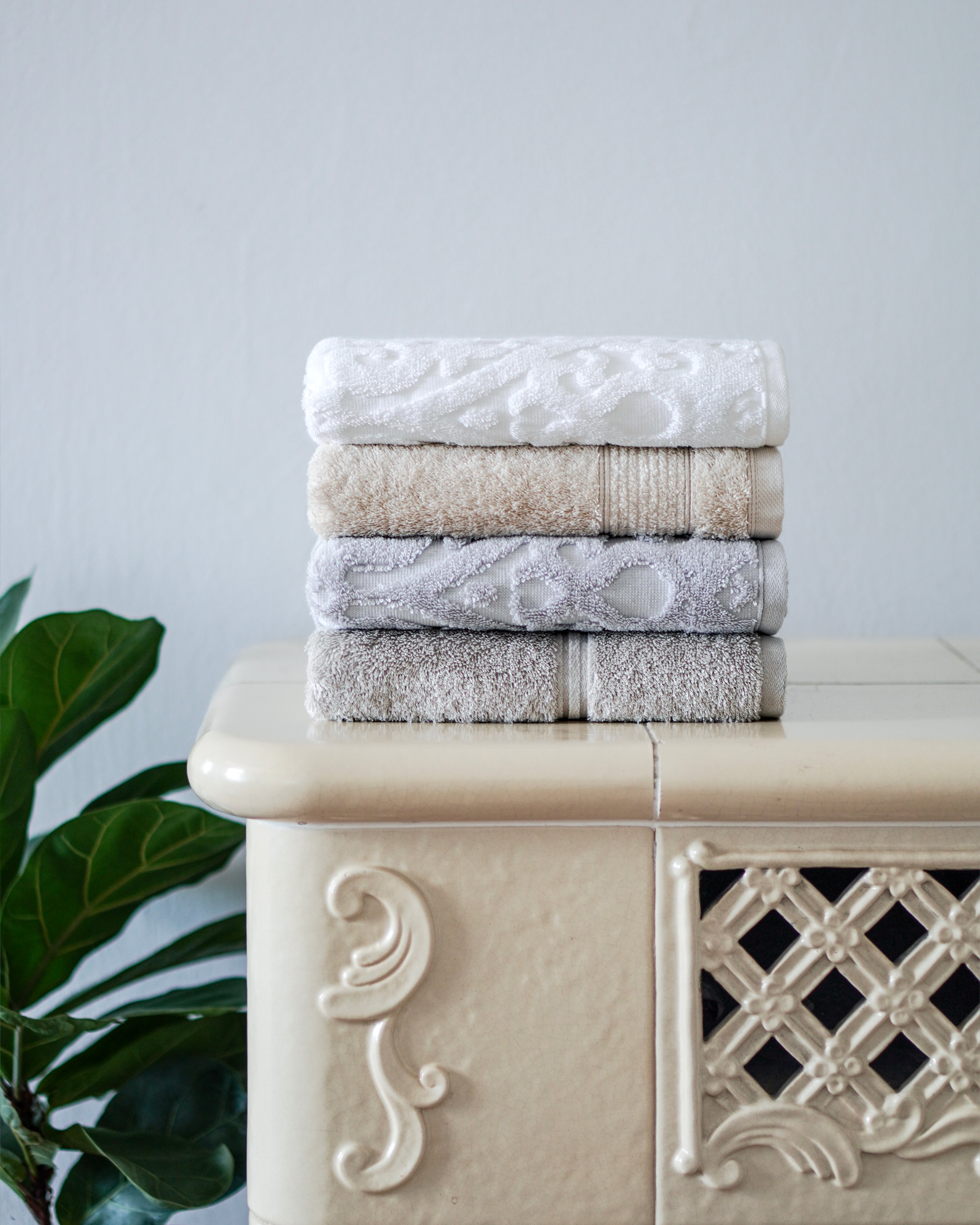 Gestapelte Handtücher in neutralen Farben auf dekorativer Kommode