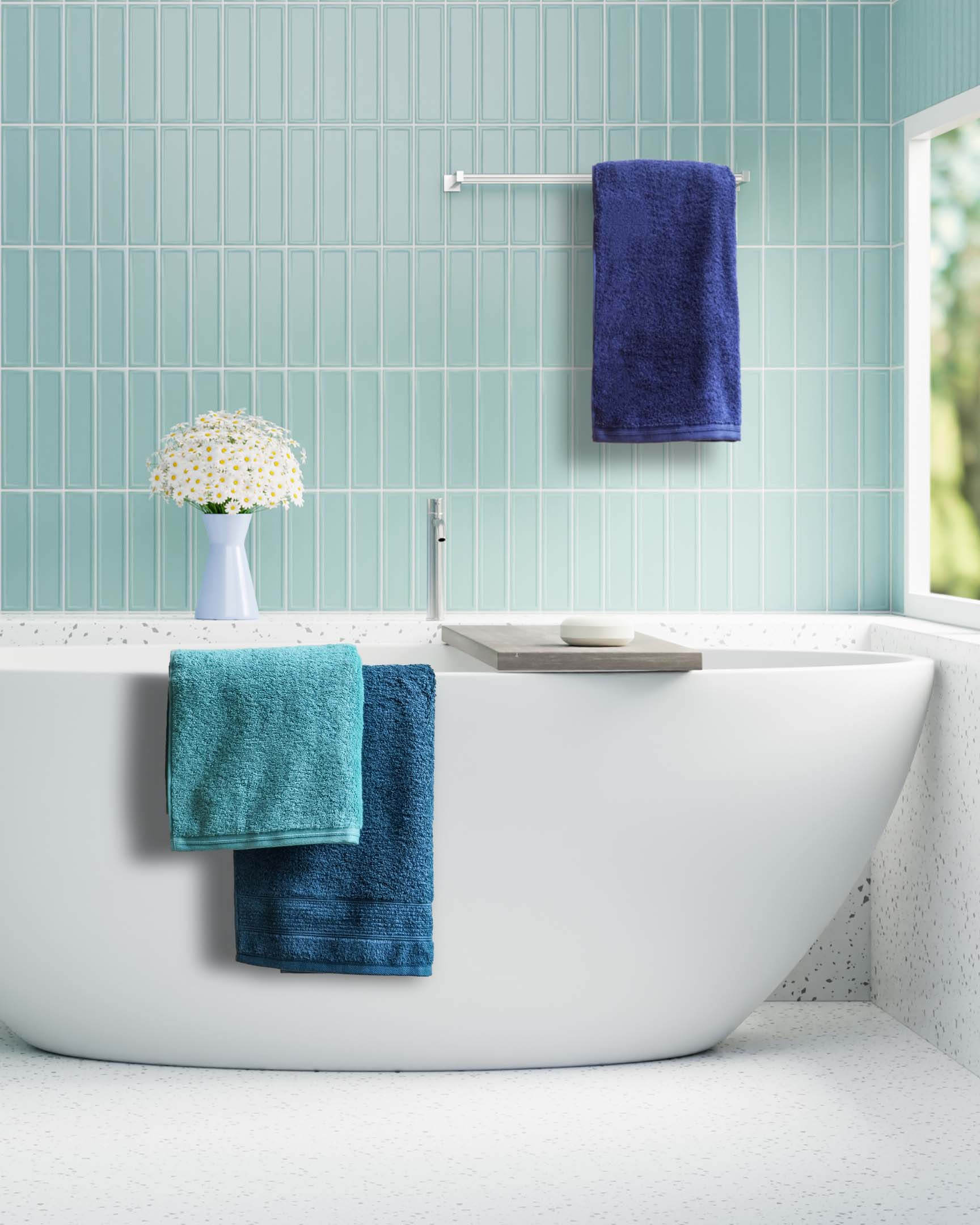 Badewanne mit farbigen Handtüchern vor türkis gefliester Wand