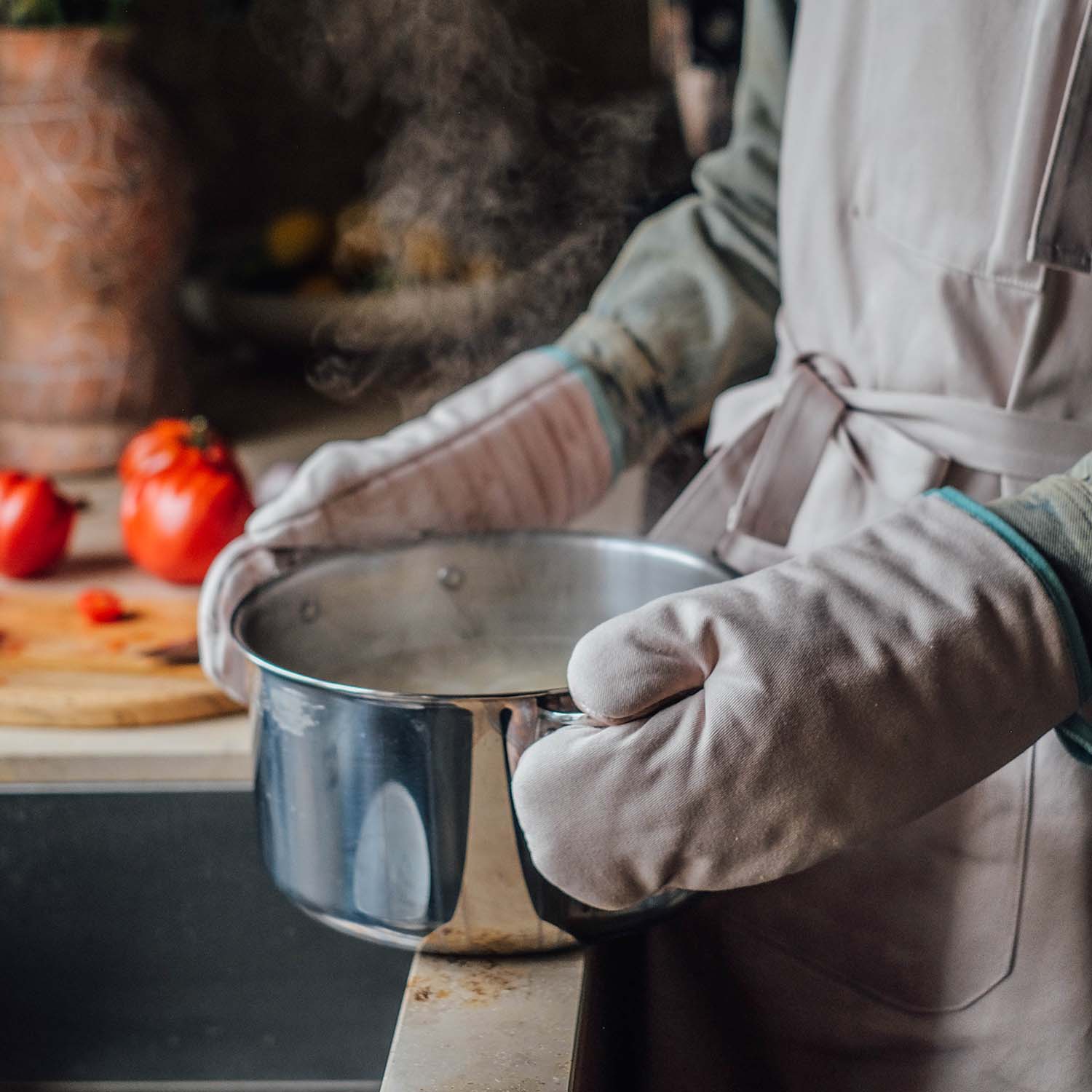 Person mit Ofenhandschuhen hält heißen Kochtopf in moderner Küche – sicheres Kochen mit hochwertigen Küchenhandschuhen