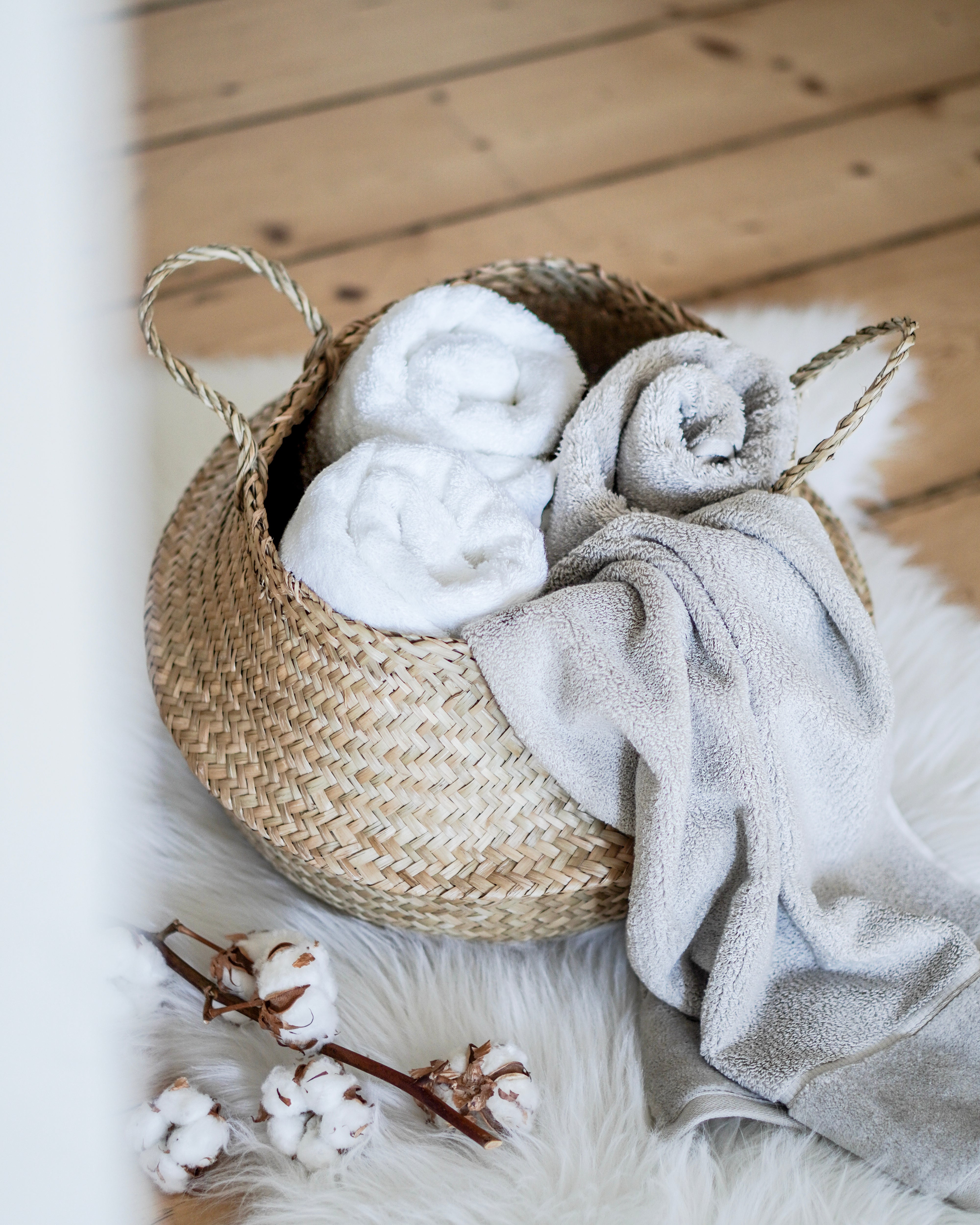 Geflochtener Korb mit eingerollten Handtüchern auf weichem Teppich